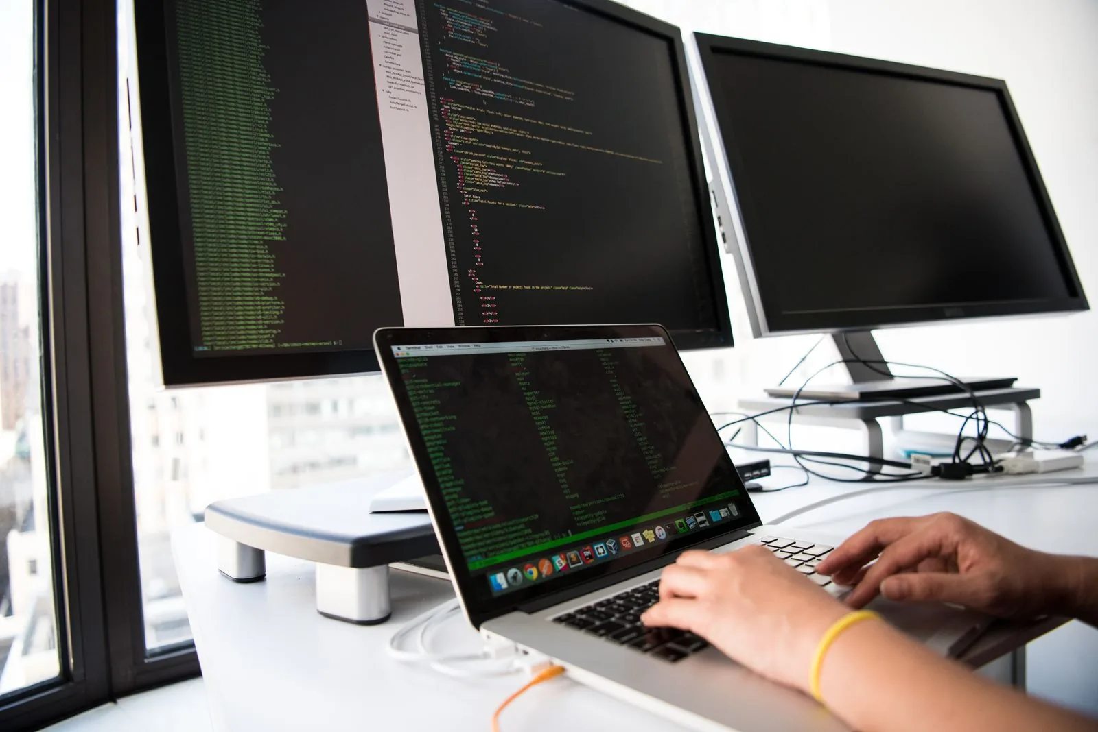 Mains sur un clavier d'ordinateur portable, écran de code