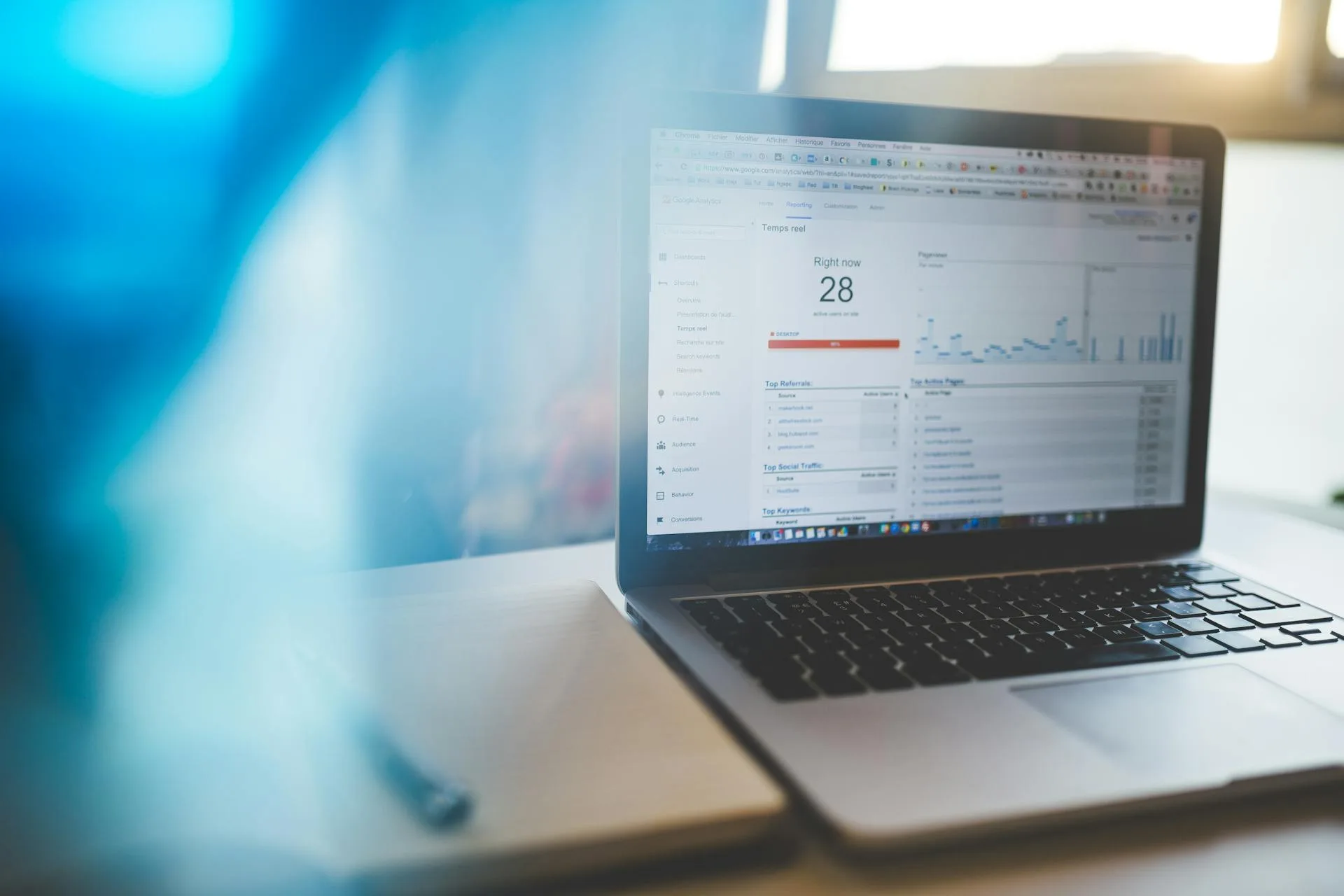 MacBook Pro affichant un tableau de bord Google Analytics sur un bureau en bois clair