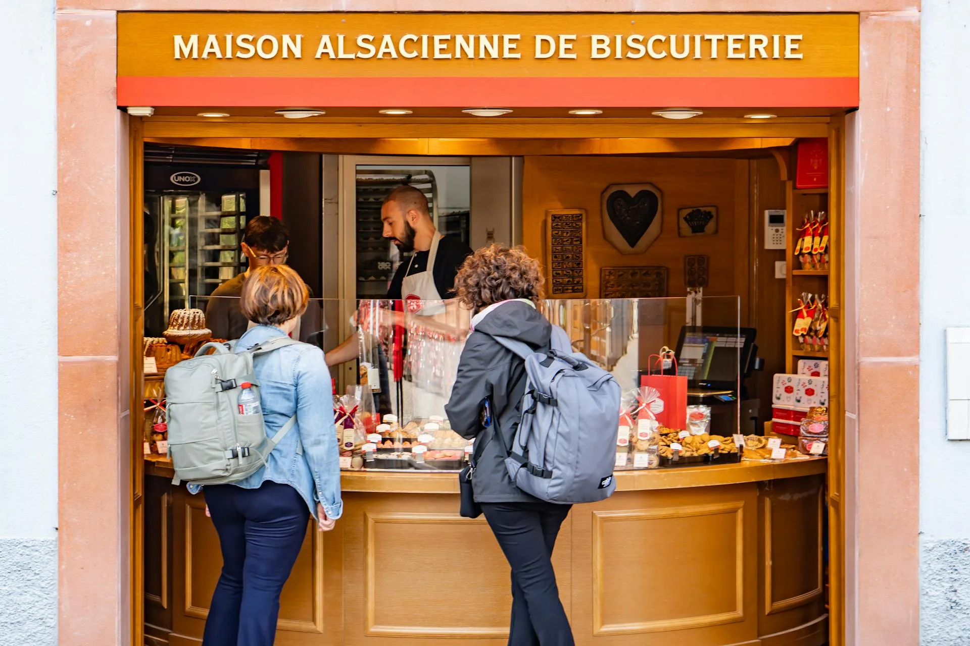 Devanture d'une boulangerie alsacienne à Colmar en France avec clients devant une vitrine de pâtisseries locales