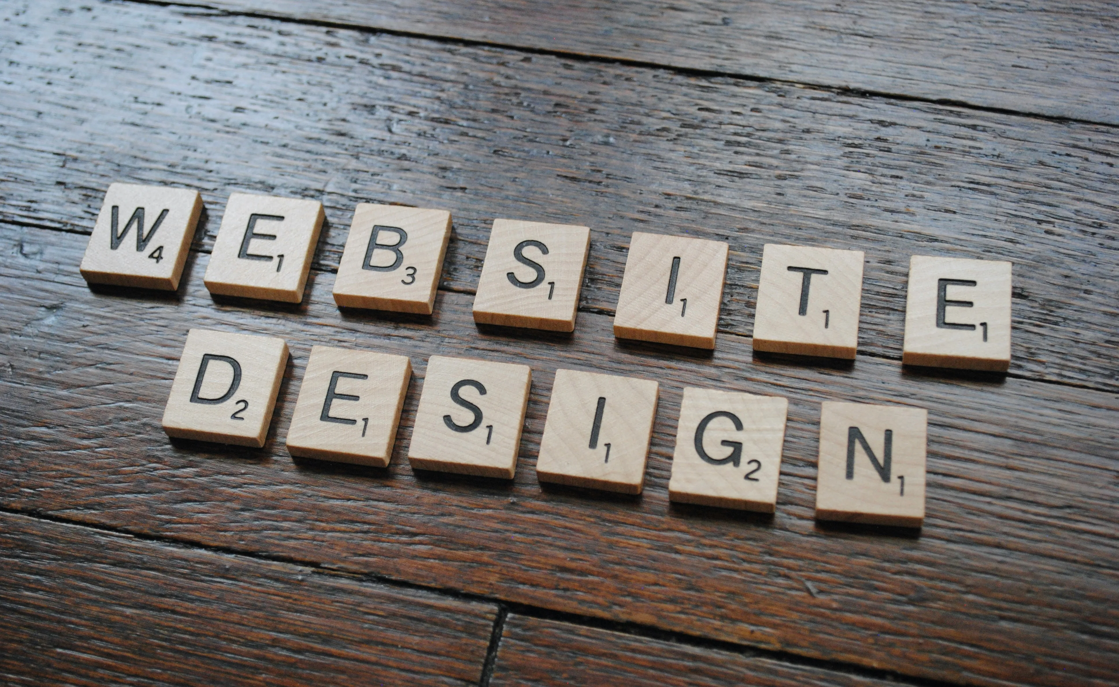 Lettres Scrabble alignées sur un plan en bois formant les mots website design