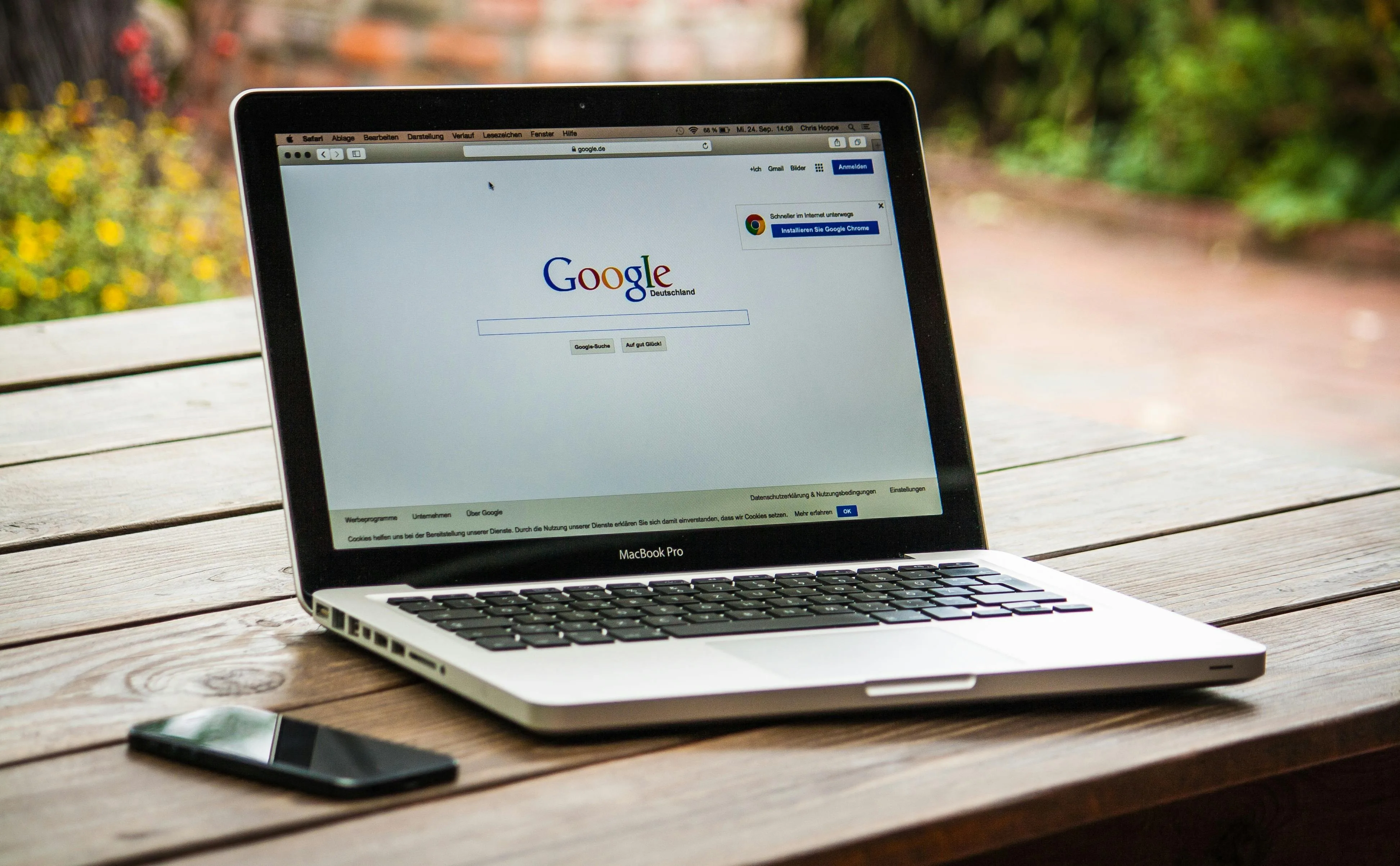 MacBook Pro ouvert sur la page Google posé sur une table en bois en extérieur