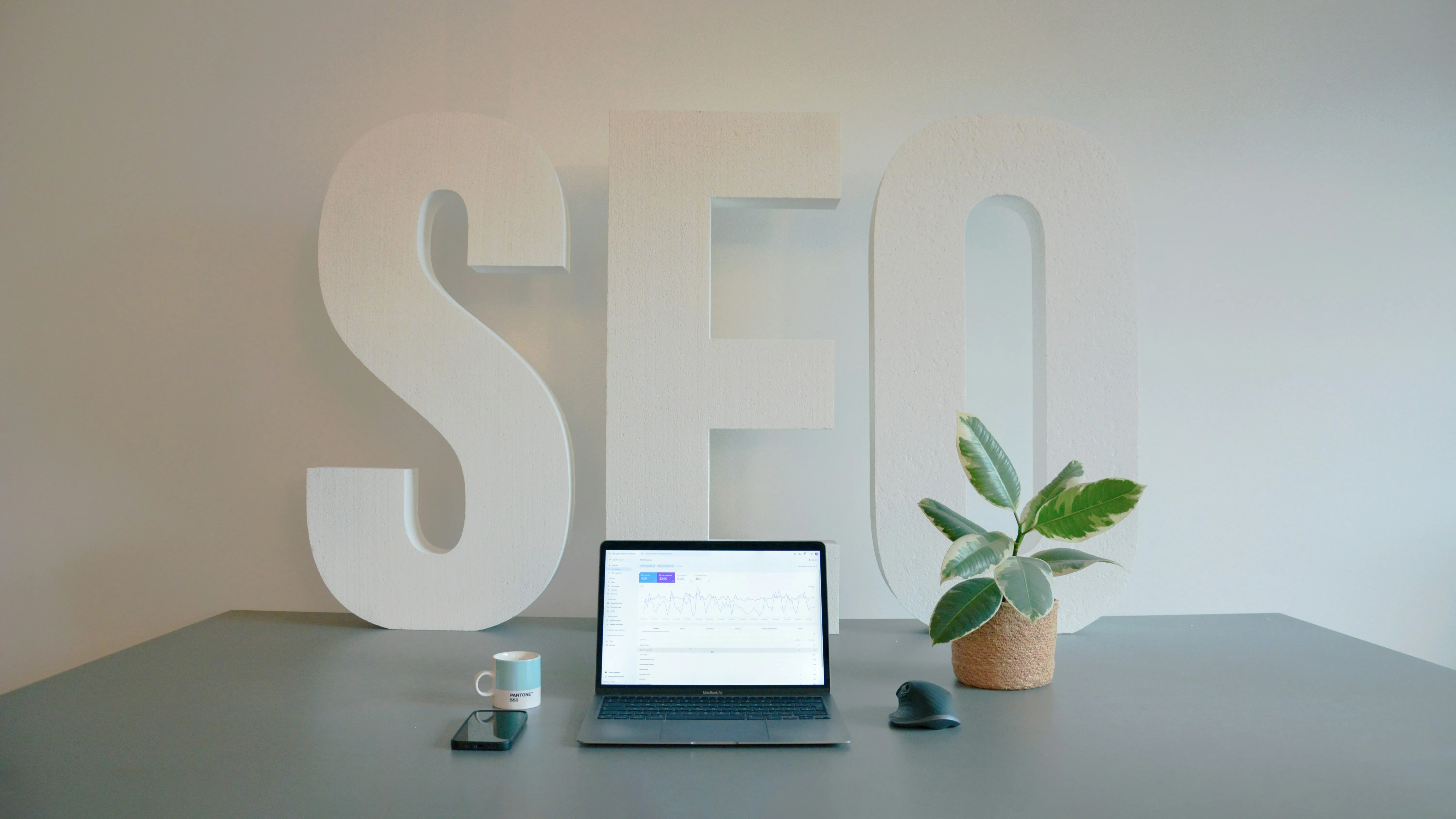 Sculpture murale aux lettres SEO surplombant un bureau avec ordinateur portable et plante verte