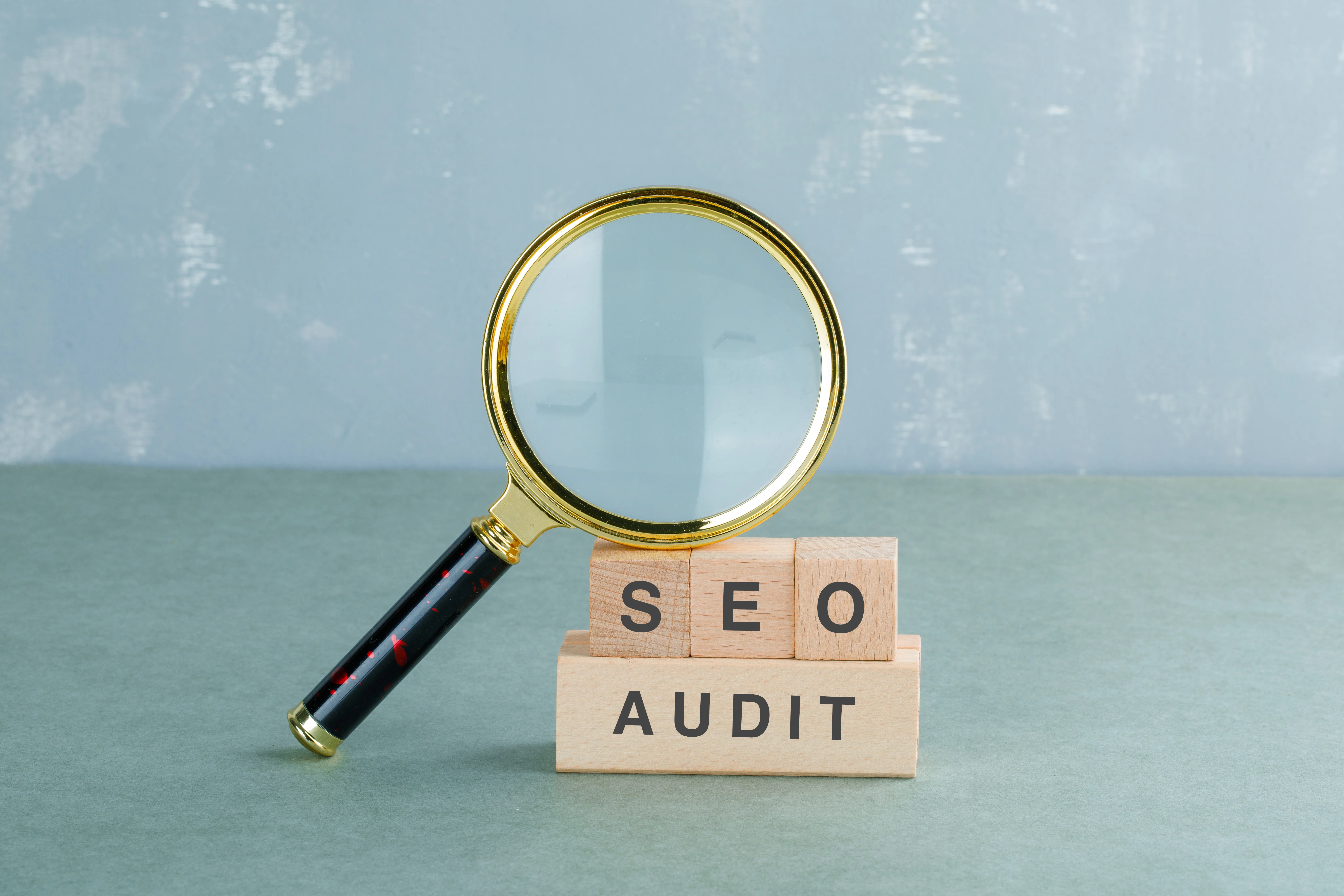 Loupe sur des cubes en bois formant les lettres SEO AUDIT, audit de référencement préalable