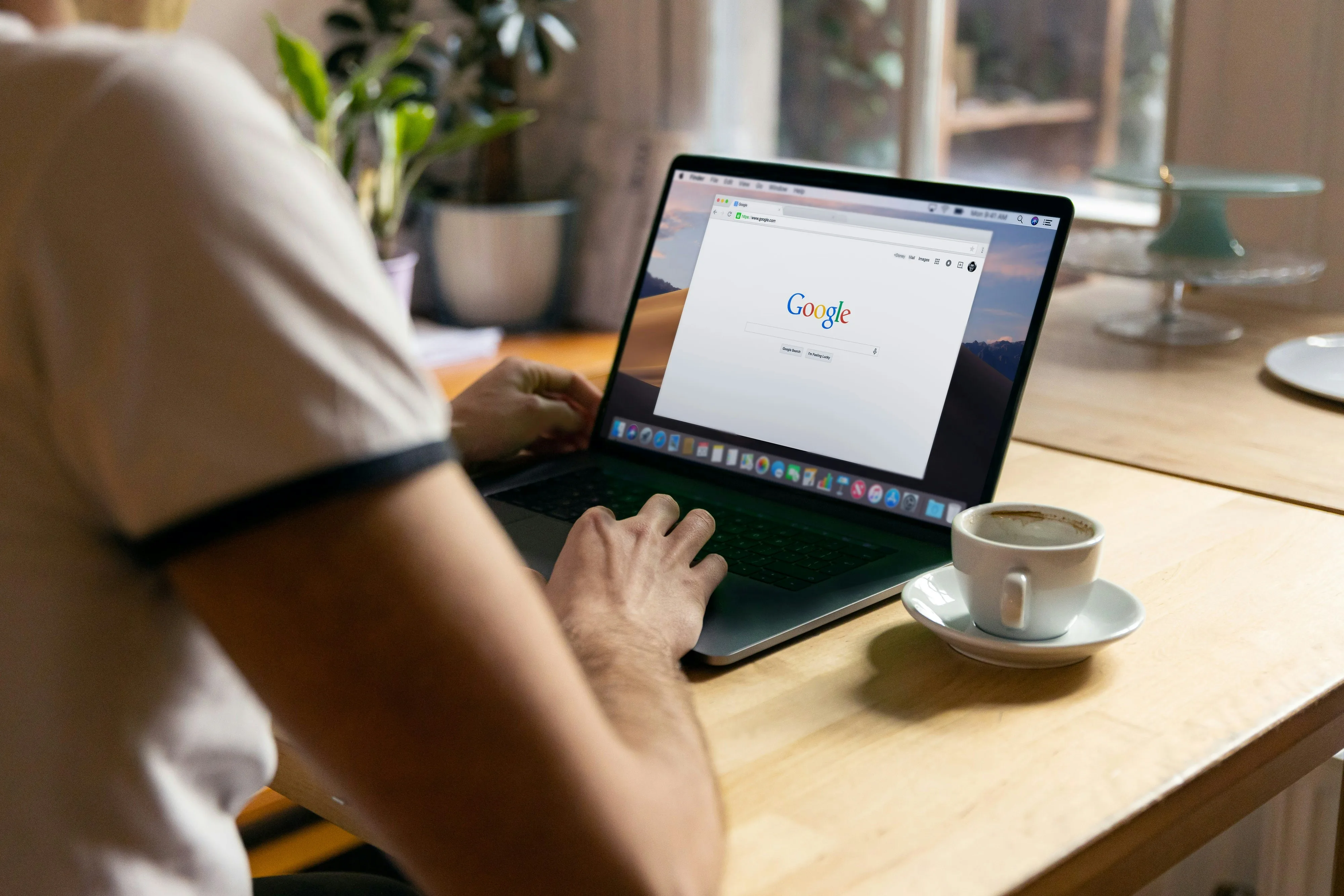 Personne effectuant une recherche sur la page d'accueil Google depuis un ordinateur portable